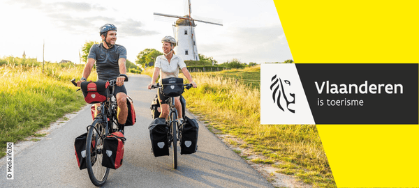 Afbeelding van man aan het wandelen en vrouw zittend op een bankje met fietsen achter hen.
